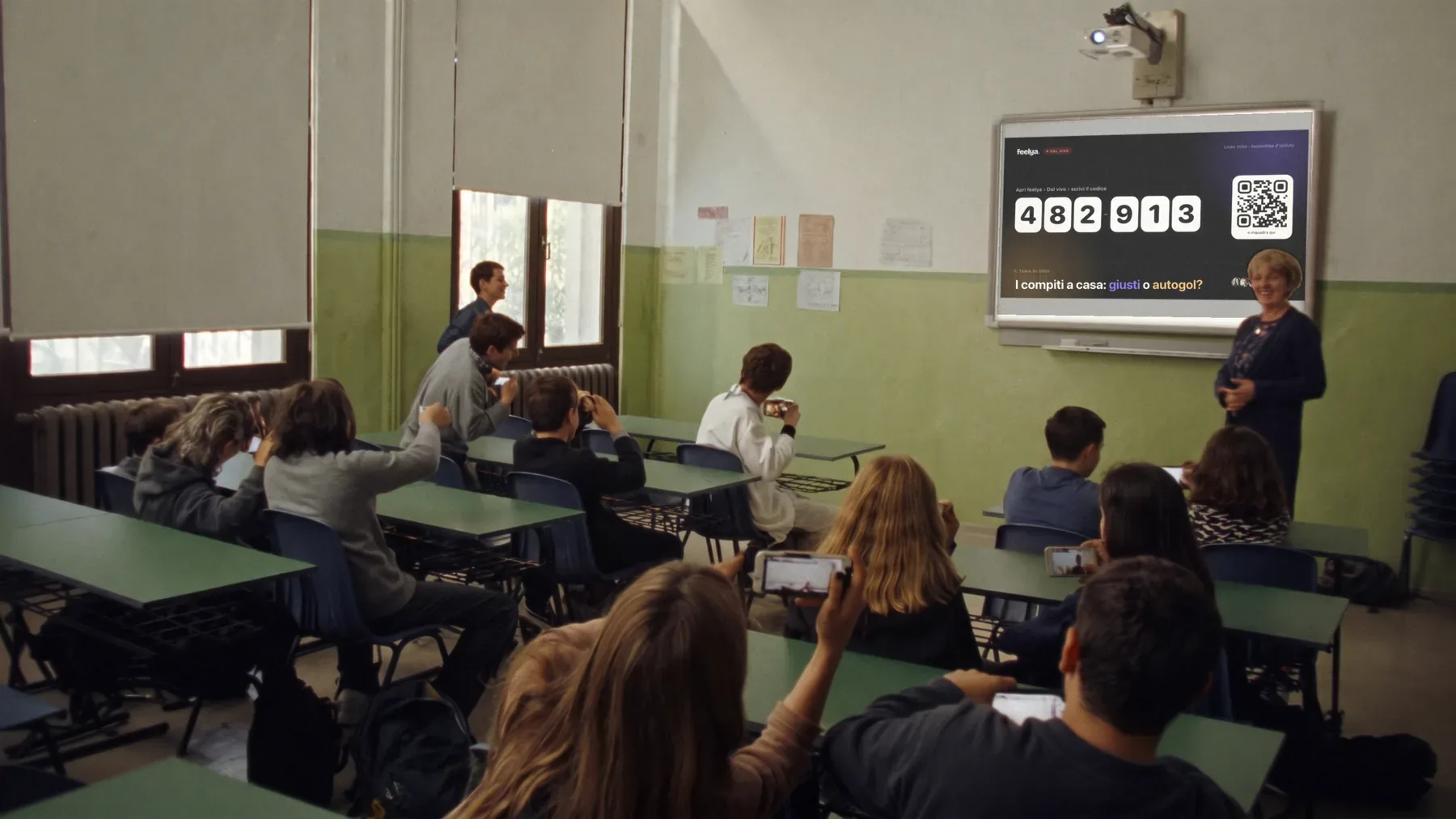 A classroom with the smartboard on: the code and QR to join the debate on screen, students scanning it with their phones
